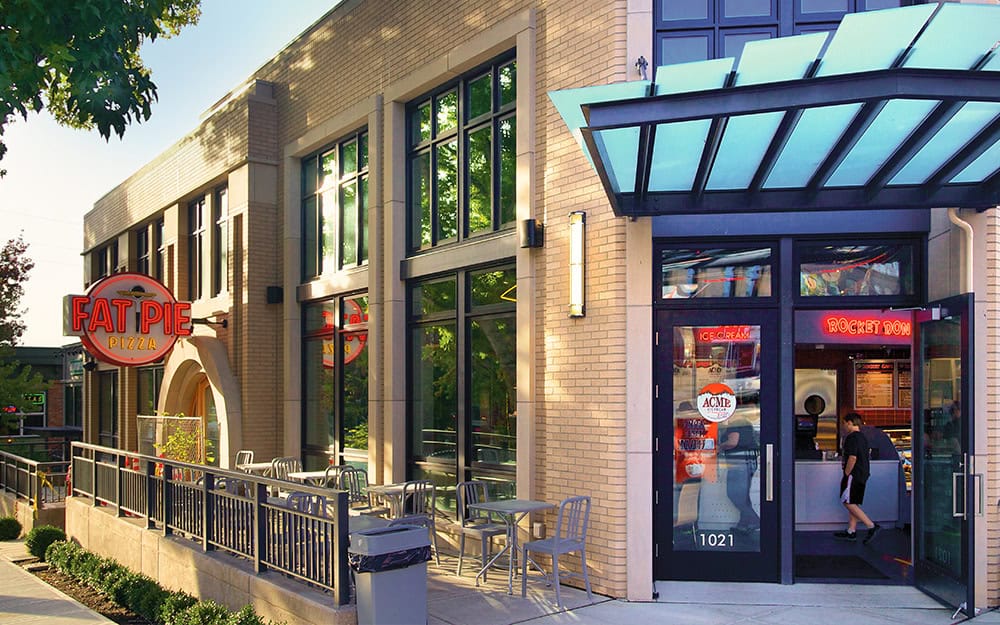 Modern commercial building with glass facade and outdoor seating area.