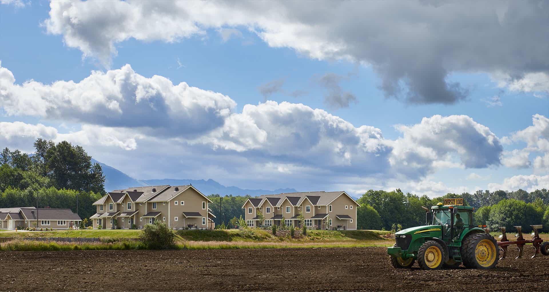 Modern residential housing development with green landscape and tractor.