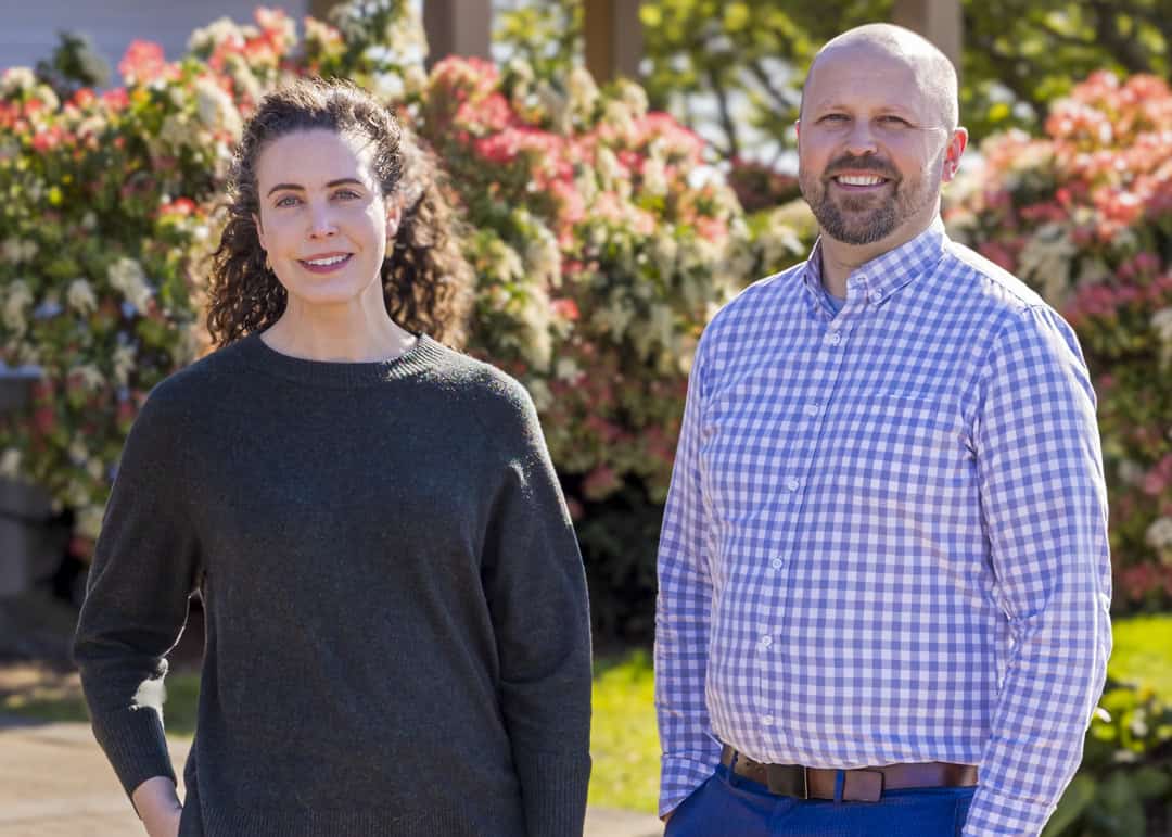 Architectural team at RMC Architects standing outdoors in front of flowering bushes.