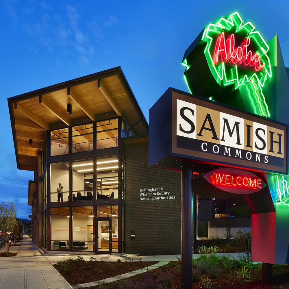 Modern building with glass facade and neon 'Aloha' sign at dusk.