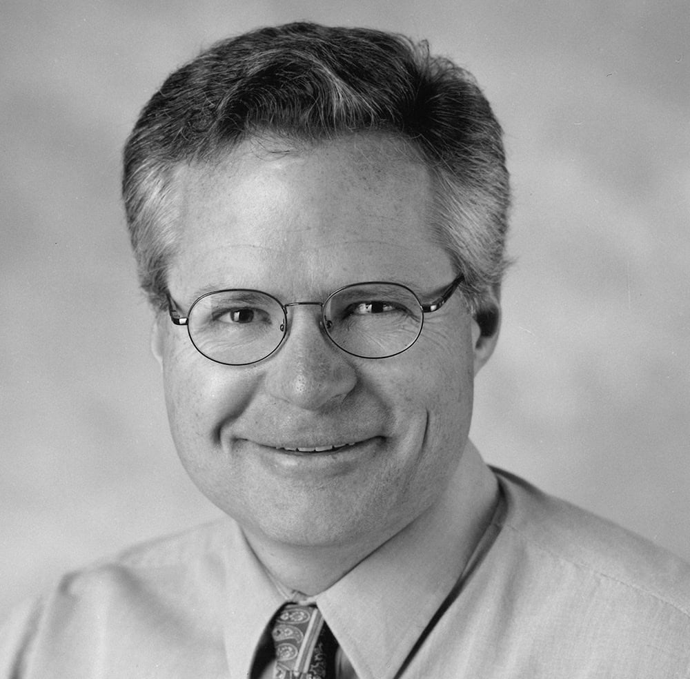 Black and white portrait of a smiling male architect with glasses.